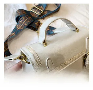 Détail du sac bandoulière crème avec cuir texturé et sangle jacquard bleu et or
