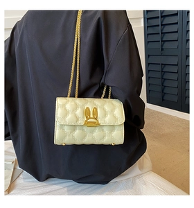 Detail of cream quilted bag featuring heart stitching and a golden rabbit metal clasp