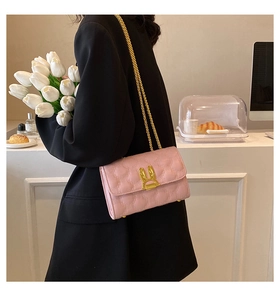 Close-up of pink quilted leather bag with golden rabbit ear buckle and chain strap
