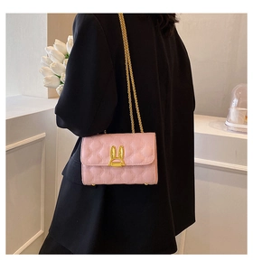 Detail of pink quilted leather bag with golden bunny lock and elegant chain strap
