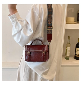 Détail du sac bandoulière vintage rouge foncé avec double boucles et bandoulière imprimée