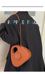 Detail view of Ripple Bag brown quilted leather texture and unique handle on black blazer