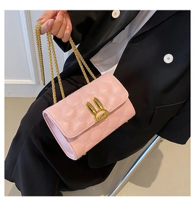 Detail of pink heart-quilted crossbody bag featuring a golden bunny ear twist lock