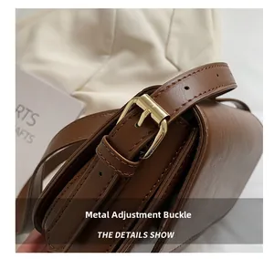 Detail shot of the pale gold adjustable hardware buckle and brown leather strap texture