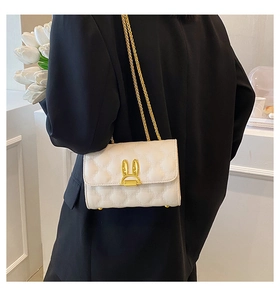 Quilted white shoulder bag with golden rabbit clasp and chain strap on a model