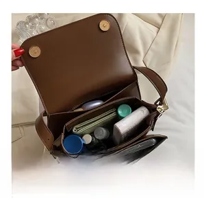 Interior view of brown leather crossbody bag showing spacious compartments and magnetic clasp
