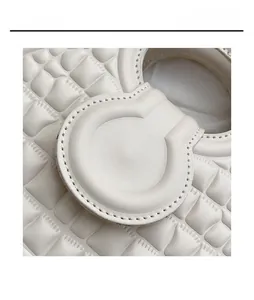 Macro view of creamy white handbag with crocodile embossing and fine stitching detail