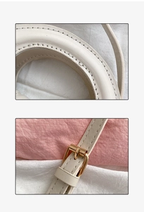 Detailed view of beige handbag handle stitching and adjustable golden metal buckle