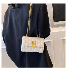 Detail of cream quilted crossbody bag with golden rabbit buckle and chain strap