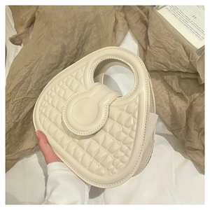 Close-up of cream white handbag featuring crocodile pattern and unique heart shape