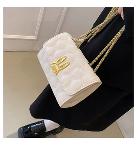 Close-up of quilted white shoulder bag with golden rabbit ear buckle and chain straps