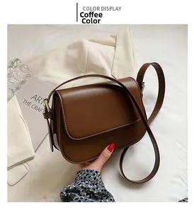 Detail view of coffee brown minimalist leather crossbody bag on a white blazer