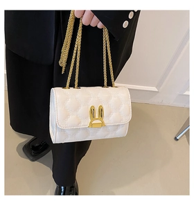 Detail of white quilted handbag featuring a unique gold rabbit-shaped metal clasp