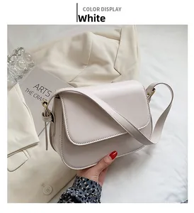 Close-up of a minimalist white flap crossbody bag with fine shoulder strap and metal hardware