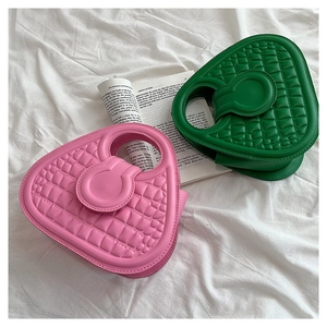 Detail of pink and green crocodile-embossed leather handbags with unique cutout handles