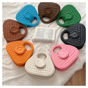 Flat lay of small square tote bags in eight colors including green, tan, and orange