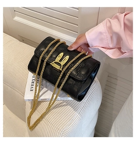Detail of black quilted crossbody bag featuring golden rabbit lock and embossed leather