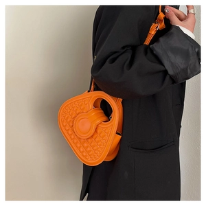 Close-up of bright orange crocodile embossed handbag with unique circular handle on model