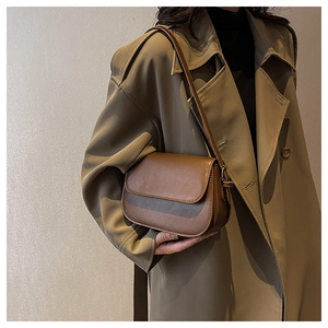 Brown leather saddle bag styled with a classic trench coat for a chic vintage look