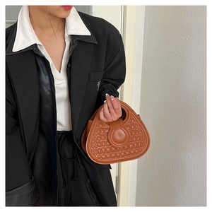 Close-up of brown embossed semi-round handbag with stylish ring buckle detail