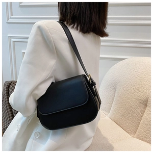 Model view of black glossy half-moon flap bag with golden hardware and adjustable strap