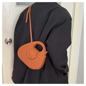 Close-up of caramel quilted leather bag with unique circular handle and sleek shoulder strap