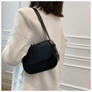 Side view of black leather shoulder bag on white suit with gold metal buckle detail