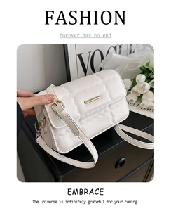Nahaufnahme der weißen Steppledertasche mit goldenem Metallverschluss vor minimalistischem Dekor
