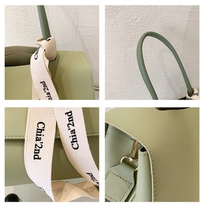 Detail of pea green leather tote showing golden hardware and woven ribbon handle