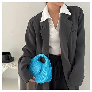 Detail of bright blue croc-embossed handbag with integrated handle on a grey blazer