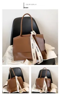 Detailed view of a brown leather shoulder bag featuring a branded white woven decorative strap