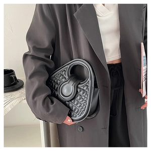 Detail of black crocodile texture mini handbag held by model in stylish office outfit