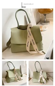 Detail view of a light green matte leather tote bag featuring a decorative logo ribbon