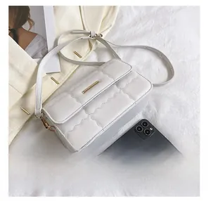 Detailansicht der weißen Stepptasche mit goldener Schnalle und Smartphone-Größenvergleich