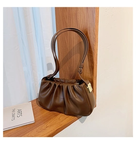 Détail du sac plissé marron avec boucle dorée élégante et texture de cuir raffinée
