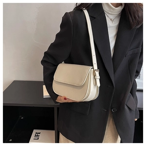Chic cream leather crossbody bag with flap closure and gold buckle shown on model