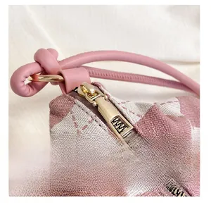 Detail of pink and white checkered bag featuring a smooth gold zipper and knotted handle