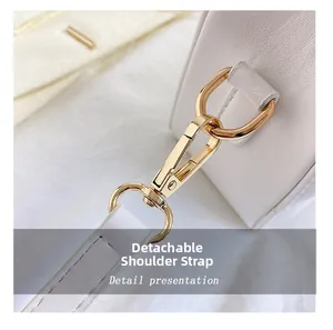 Details des goldenen Karabinerverschlusses und des weißen Lederriemens mit Ziernähten