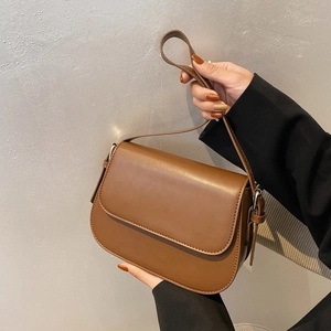 Detail of caramel brown leather shoulder bag with sleek flap and vintage round silhouette