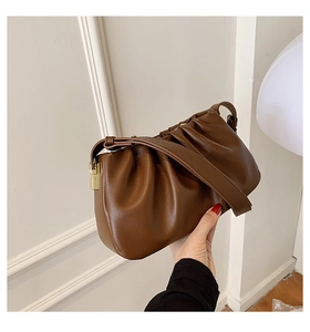 Détail d'un sac plissé marron foncé avec boucle métallique dorée et bandoulière
