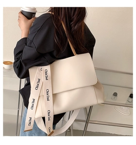 Detail of creamy white crossbody bag with wide logo-printed woven shoulder strap