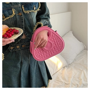 Pink crocodile-embossed heart handbag with denim-wrapped handle on a white bed