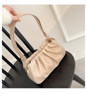 Détail du sac à main plissé beige avec ferrures dorées et texture nuageuse
