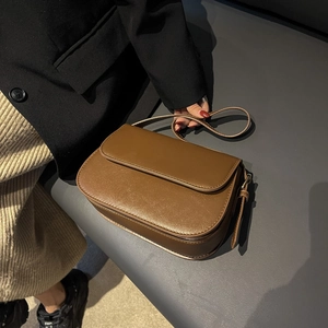 Chic brown synthetic leather crossbody bag with flap cover on a stylish model