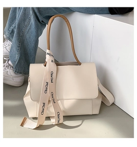 Detail view of cream tote bag with brown handles and branded ribbon decoration
