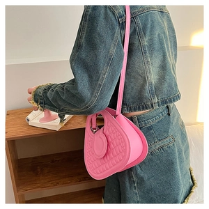 Close-up of pink heart-shaped bag with quilted texture and slender shoulder strap
