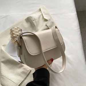 Detail view of cream white PU leather crossbody bag featuring refined grainy texture