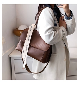 Detail of dark brown leather underarm bag with a wide jacquard textile shoulder strap