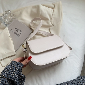 Fashionable cream white crossbody bag with gold hardware in a minimalist lifestyle setting