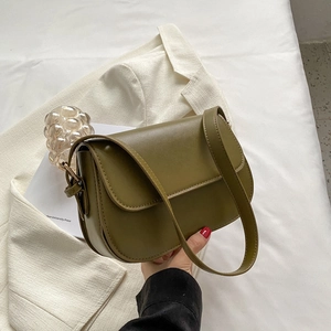 Close-up of olive green leather crossbody bag with smooth finish and metal hardware detail